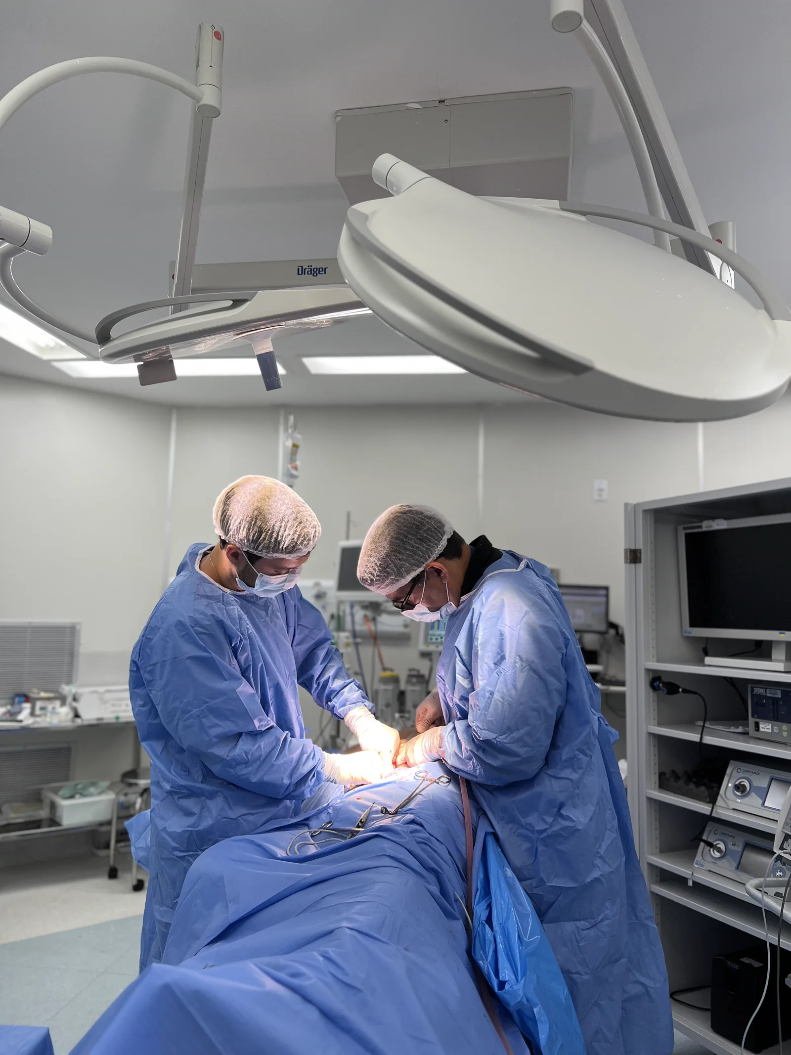 Dr. Ricardo Freitas e outro médico realizando um procedimento em centro cirúrgico
