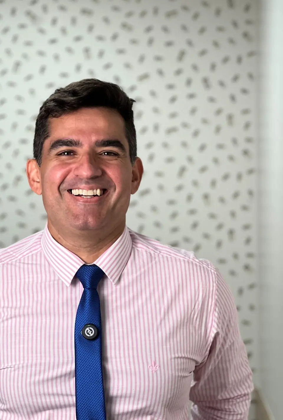 Retrato do Dr. Ricardo Freitas sorrindo, de camisa listrada rosa e gravata azul