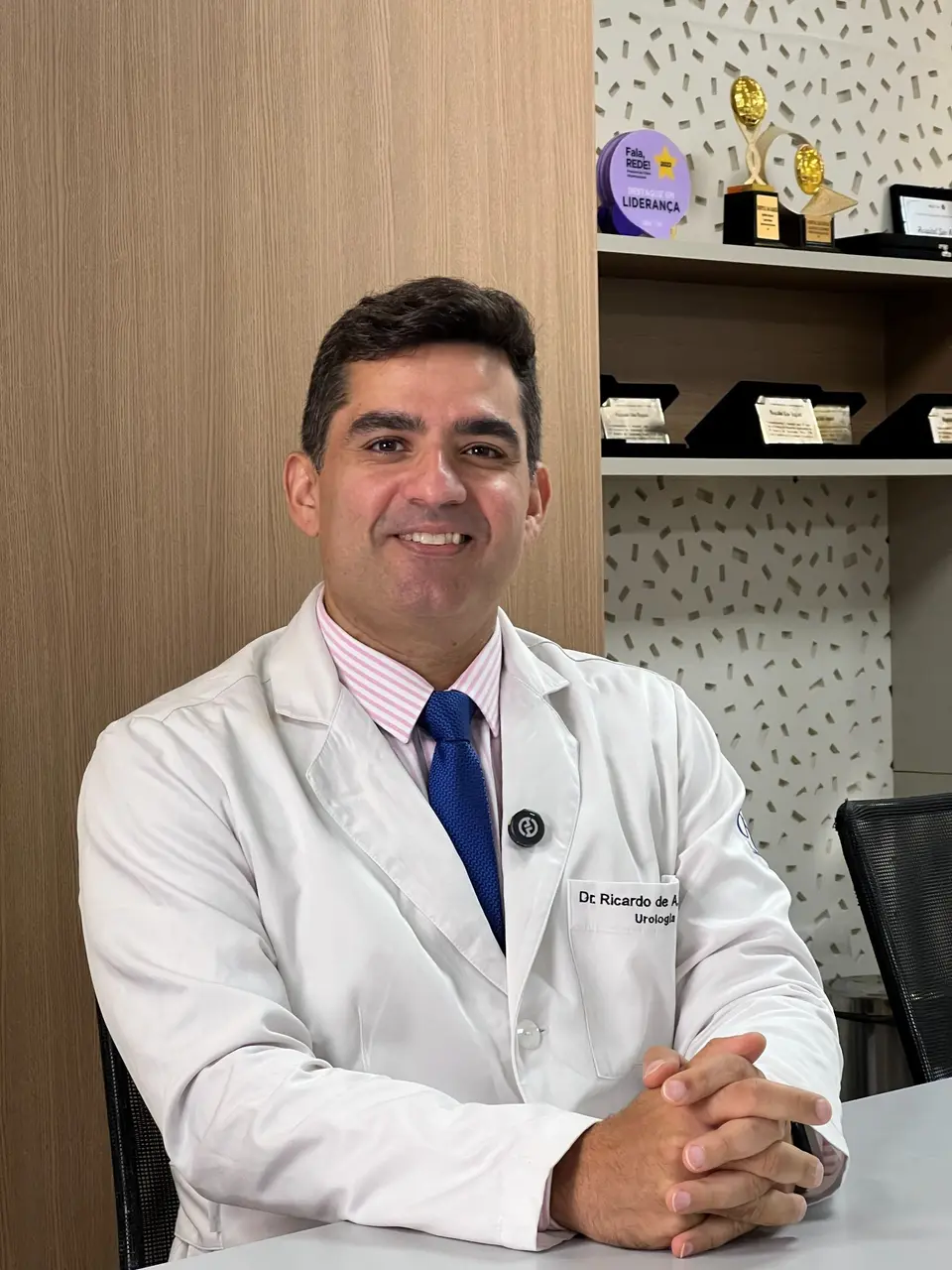 Dr. Ricardo Freitas de jaleco, sentado à mesa do consultório
